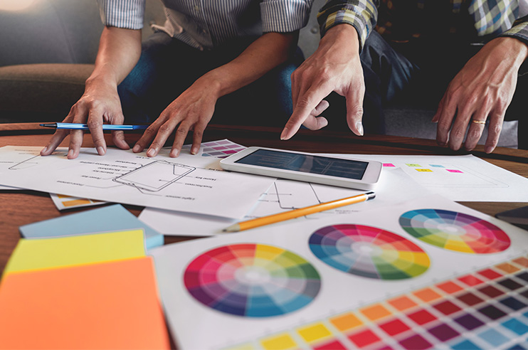 Duas pessoas a planear um projeto com vários materiais em cima de uma mesa.